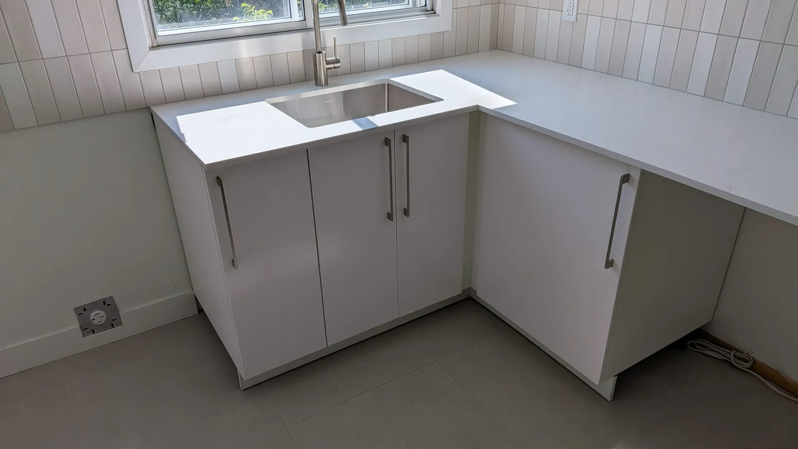 Armoires d’évier blanches IKEA SEKTION avec comptoir en quartz et dosseret en céramique, cuisine de Brossard