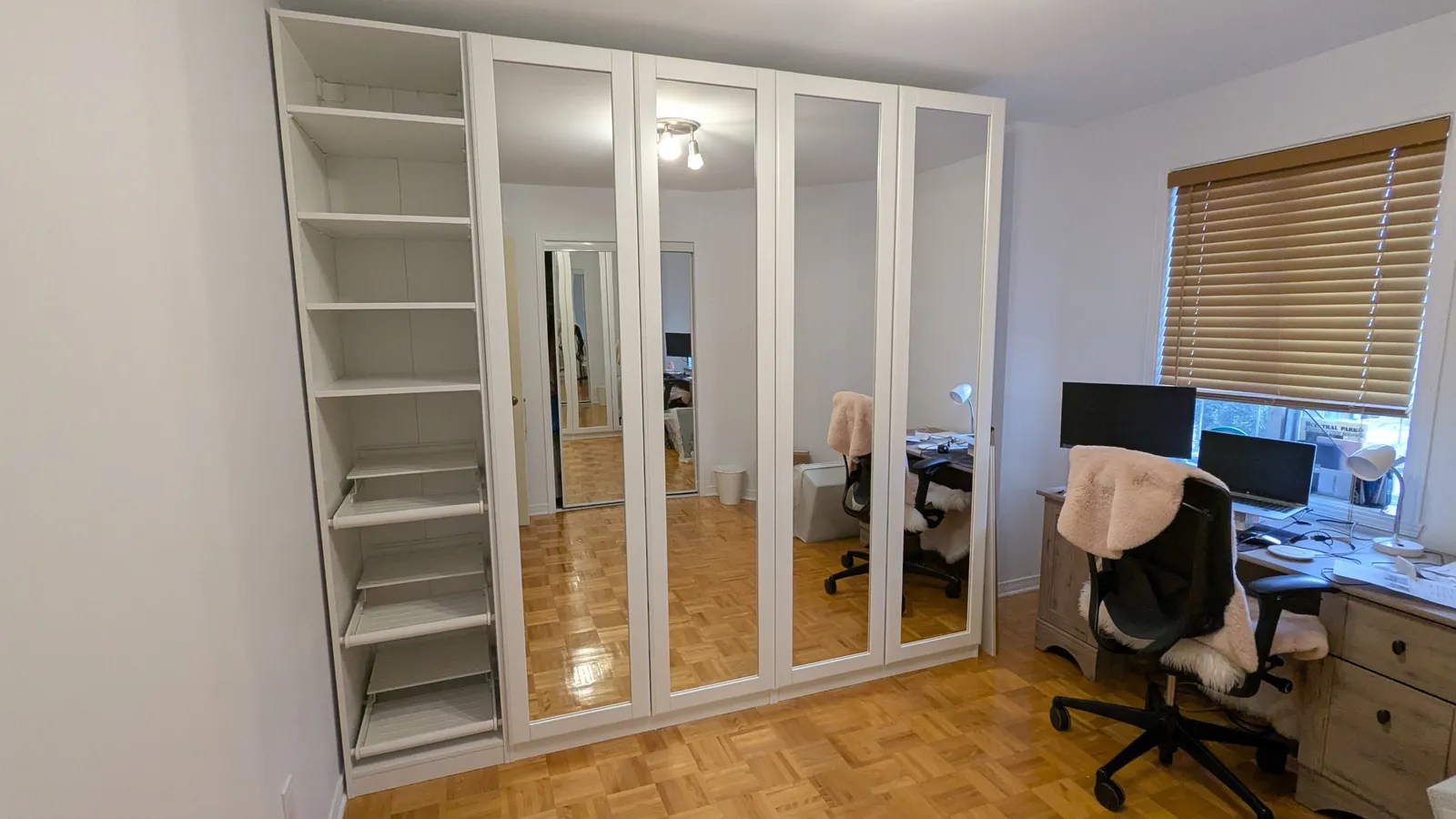 IKEA PAX wardrobe in Saint-Laurent, Montreal, with four framed mirror doors closed next to a tall open shelving unit with pull-out shelves