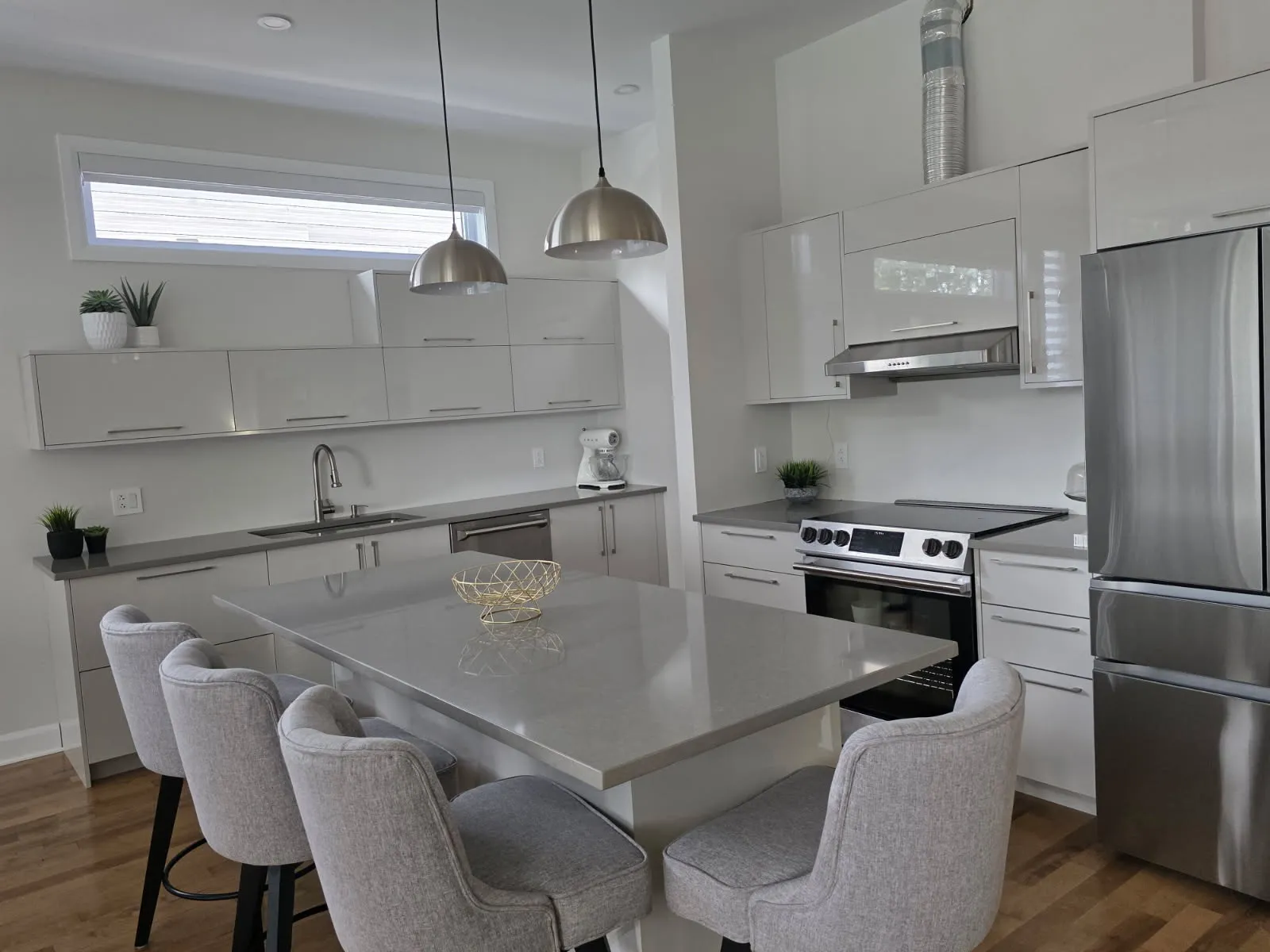 Cuisine RONA en L à Laval avec îlot, réfrigérateur en inox et suspensions