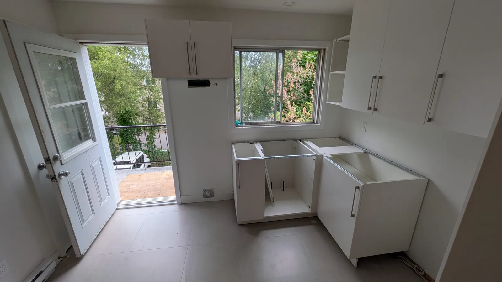 Armoires hautes et basses blanches en cours d’installation près d’une fenêtre et d’une porte de balcon, Brossard