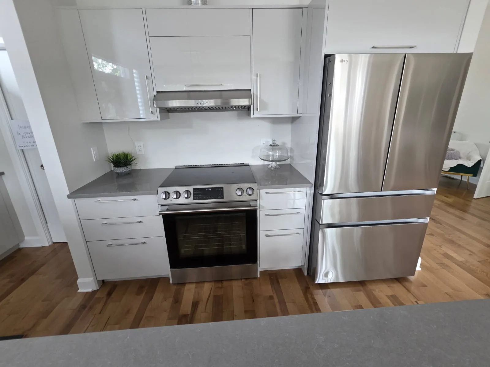 Cuisinière électrique en inox, hotte et réfrigérateur à portes françaises dans une cuisine blanche moderne à Laval